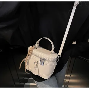 Close-up of elegant cream-white box bag with zipper and decorative tag