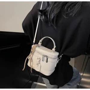 Close-up of a stylish white box vanity handbag featuring a top handle and shoulder strap