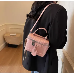 Detailed close-up of a stylish pink box-style handbag worn with a chic black blazer.
