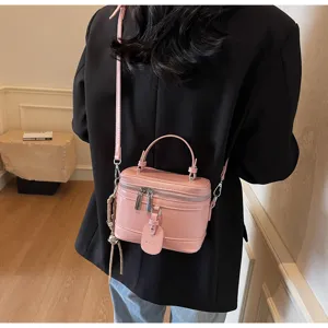 Detail view of a chic pink box handbag styled with a black blazer for a modern look.