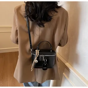 Detail of a chic black box handbag styled with a tan blazer for a modern look.