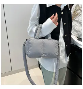 Grijze gewatteerde nylon handtas en crossbodytas getoond in een modieuze casual outfit