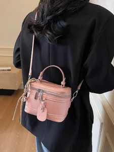 Elegant pink minimalist box-style crossbody bag with adjustable strap and top handle.