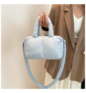 Detailweergave van een lichtblauwe, gewatteerde nylon handtas en crossbodytas voor dames