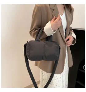 Stijlvolle zwarte gewatteerde puffer handtas van nylon gedragen door een model als detail.