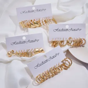 Varios sets de pendientes de aro dorados con perlas sintéticas y diseños trenzados en cartón