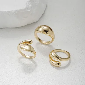Elegante set van drie onregelmatige gouden open ringen op een witte stenen ondergrond.