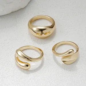 Close-up van drie gouden onregelmatige open ringen met gladde metallic afwerking en organische vormen