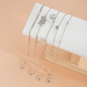 Juego de 4 tobilleras plateadas con mariposas y corazón en un soporte de joyería pro