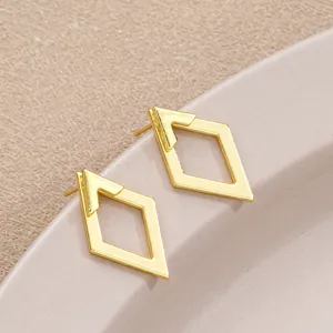Close-up of gold geometric hollow diamond earrings with double-layered design.