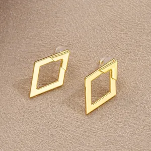 Detailed macro view of gold minimalist geometric rhombus hollow earrings with arrow detail