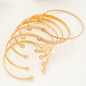 Detailed view of vintage gold-layered bangles with various textures and ball ends.