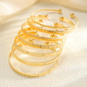 Close-up of seven vintage gold bangles with diverse engraved patterns and textures