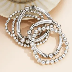 Detail van de 5-delige zilveren kralenarmbandset met gebogen metalen buizen