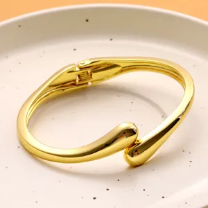 Vue détaillée d'un bracelet doré en forme de goutte d'eau avec finition métallique brillante.