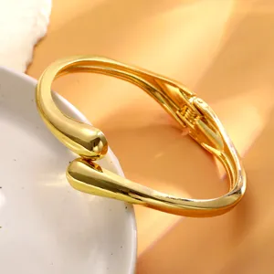 Gros plan du bracelet jonc doré avec finition métallique lisse et design en goutte