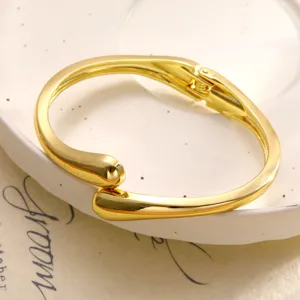 Vue détaillée d'un bracelet jonc doré en forme de goutte avec finition polie et ressort.
