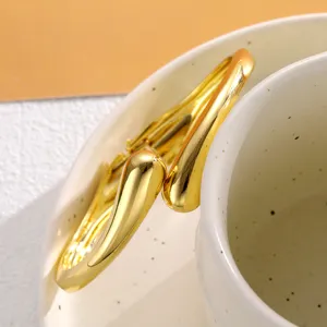 Zoom sur un élégant bracelet doré en forme de goutte d'eau au fini métallique brillant.
