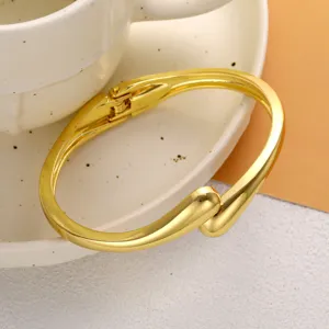 Détail d'un bracelet jonc doré profilé en forme de goutte d'eau avec une finition brillante