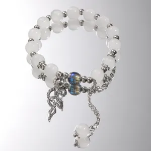 Detailed view of iridescent glass bead and butterfly charm on a white beaded bracelet