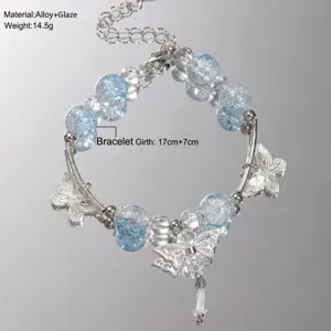 Close-up detail showing blue glaze beads and intricate silver butterfly charms on a bracelet