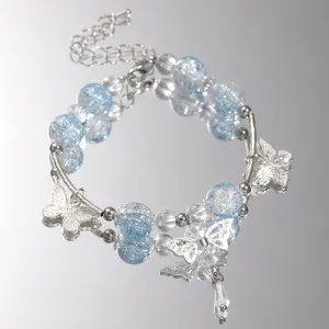 Detailed view of light blue crackle beads and silver butterfly charms on a luxury bracelet