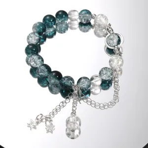 Close-up of a teal and clear glass beaded bracelet with silver star charms on a mirror.