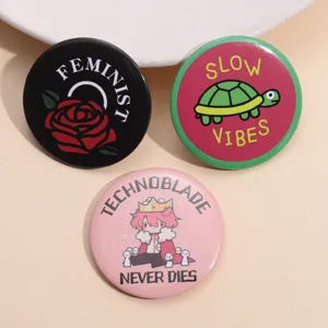Detail view of three round tinplate badges with rose, turtle, and anime character designs.