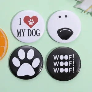 Macro shot of four dog-themed tinplate button pins with paw prints and woof text.