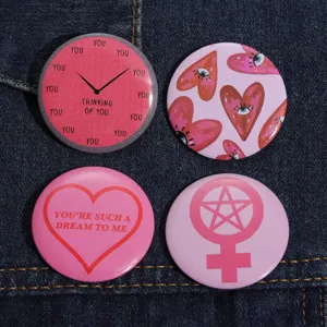 Detailed shot of four aesthetic round tinplate brooches on a dark denim fabric background.