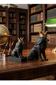 Primer plano de esculturas de leones negros geométricos con coronas doradas.
