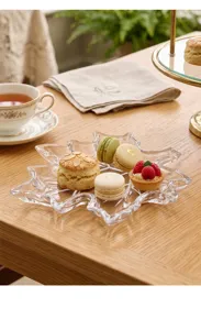 Primer plano de un plato de cristal con forma de hoja de arce y postres variados