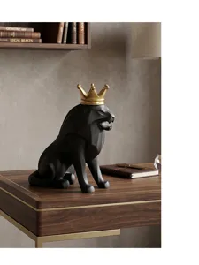 Primer plano de escultura de león negro mate con corona dorada en escritorio madera.