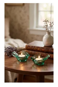 Dettaglio di due portacandele a forma di uccello in vetro verde con tealight su tavolo.