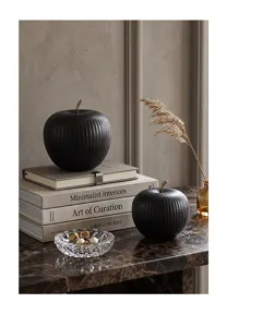 Detail view of black ribbed ceramic apple ornaments on a minimalist interior setup