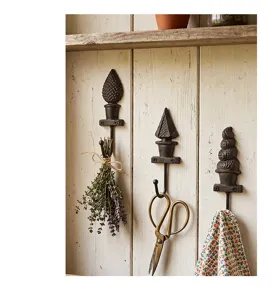 Lot de trois crochets muraux vintage en fonte aux motifs décoratifs sur fond bois
