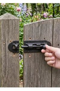 Detail view of a vintage black cast iron sliding gate latch installed on a wooden fence