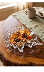 Vista detallada de un plato de vidrio con forma de hoja de arce con frutas secas y nueces