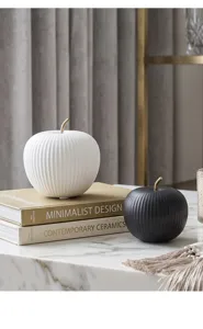 Close-up of white and black ceramic apple ornaments with ribbed texture on marble