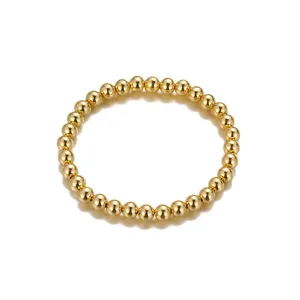 Gedetailleerde close-up van een minimalistische gouden kralenarmband op een witte basis.
