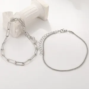 Detail view of shimmering minimalist silver anklet set featuring paperclip and fine chains