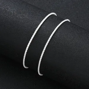 Close-up of a shimmering silver minimalist anklet chain on a black display background