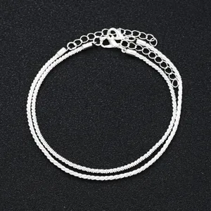 Close-up of shimmering silver-tone multi-layer anklet set featuring lobster claw clasps