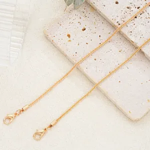 Detailed view of a gold shimmering chain with secure lobster clasps on textured stone.