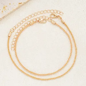 Detailed view of two shimmering gold anklets featuring adjustable lobster claw clasps.