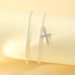 Detailed macro view of a sparkling silver-tone anklet featuring a rhinestone-studded cross pendant
