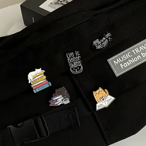 Nahaufnahme eines niedlichen Emaille-Anstecknadel-Sets mit Katzen- und Buchmotiven