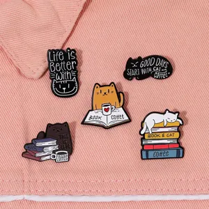 Detailansicht des Emaille-Pin-Sets mit Katzen- und Buchmotiven auf rosa Jeansstoff