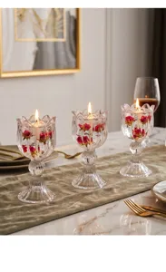 Nahaufnahme von brennenden Kerzen in eleganten tulpenförmigen Kristallglashaltern am Tisch.