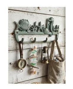 Vintage-Wandhaken aus Gusseisen mit Meerestieren an einer rustikalen weißen Holzwand